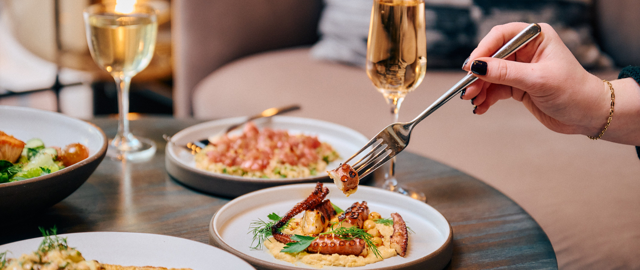 Planning dinner with friends, enjoying fine dining at a restaurant with plates of food and champagne glasses.